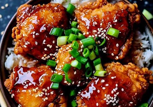 Glazed chicken on rice with green onions.