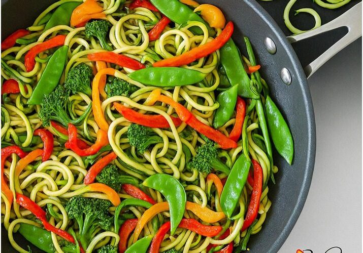 Zucchini noodles with colorful vegetables in pan.